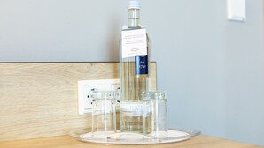 Eine Wasserflasche mit Etikett, ein Glas und ein Salzdose auf einer Holztischplatte.