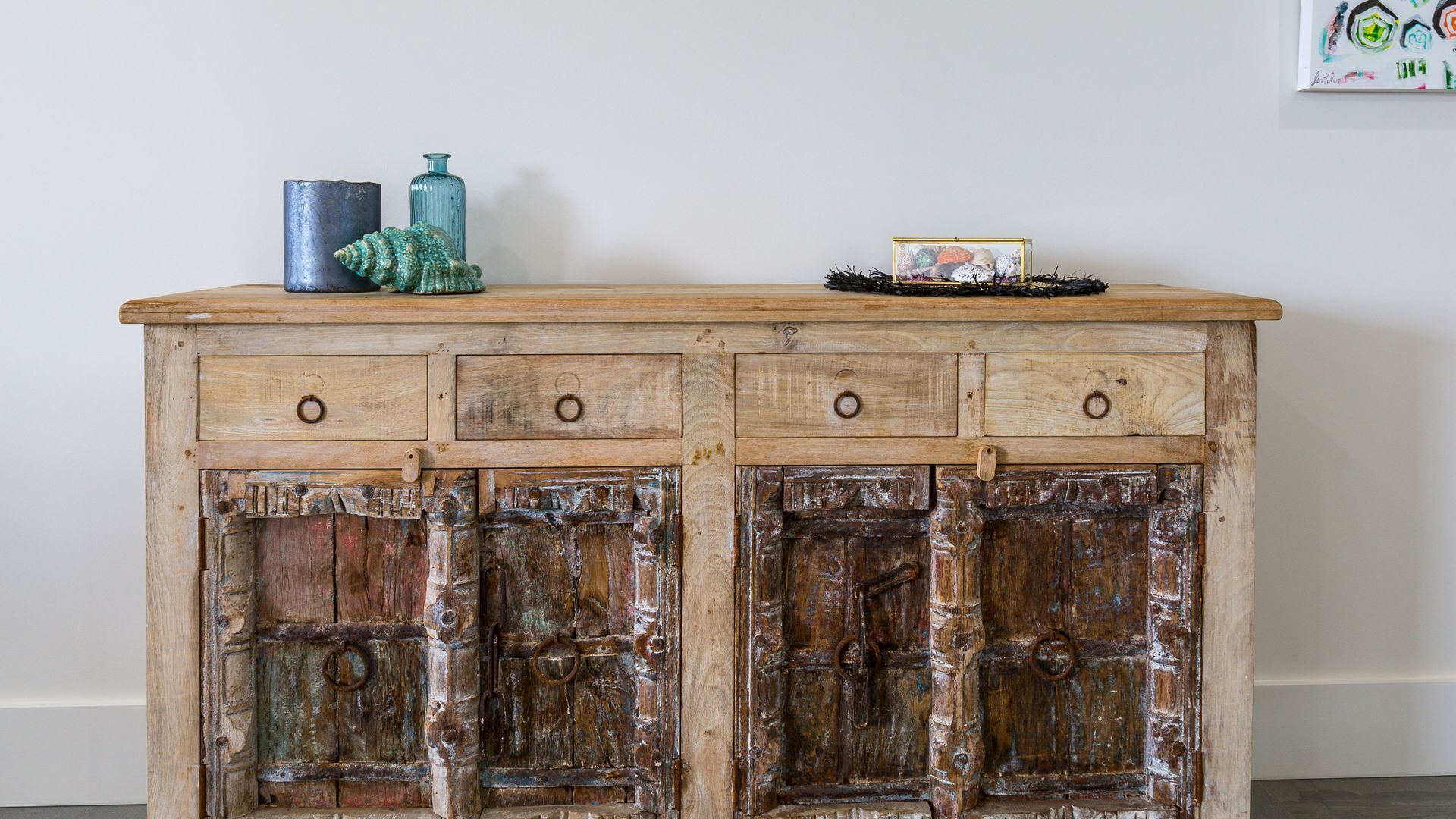 Un meuble en bois rustique doté de trois tiroirs et d’une étagère supérieure décorative.