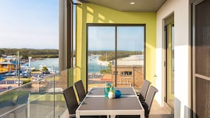 A balcony with a glass railing overlooking a marina and a river.
