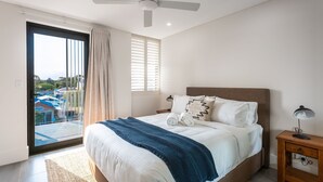 A bedroom with a bed, a nightstand, a lamp, and a view of the outside.