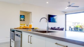 A modern kitchen with a large island, built-in oven, and a flat-screen TV mounted above the island.
