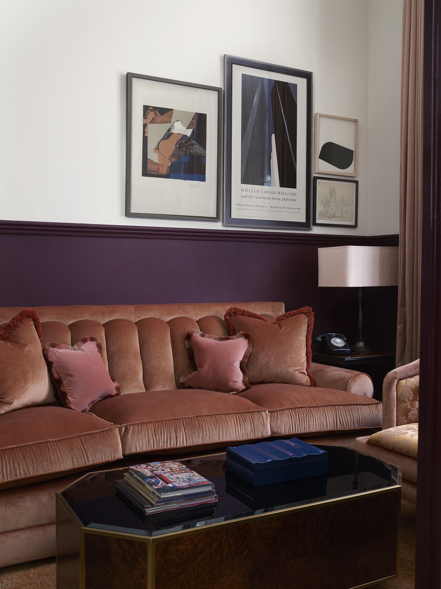 Ein Wohnzimmer mit einem braunen Sofa, einem Glastisch und gerahmten Kunstwerken an der Wand.