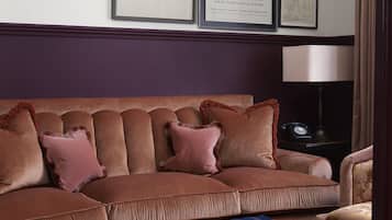 Ein Wohnzimmer mit einem braunen Sofa, einem Glastisch und gerahmten Kunstwerken an der Wand.