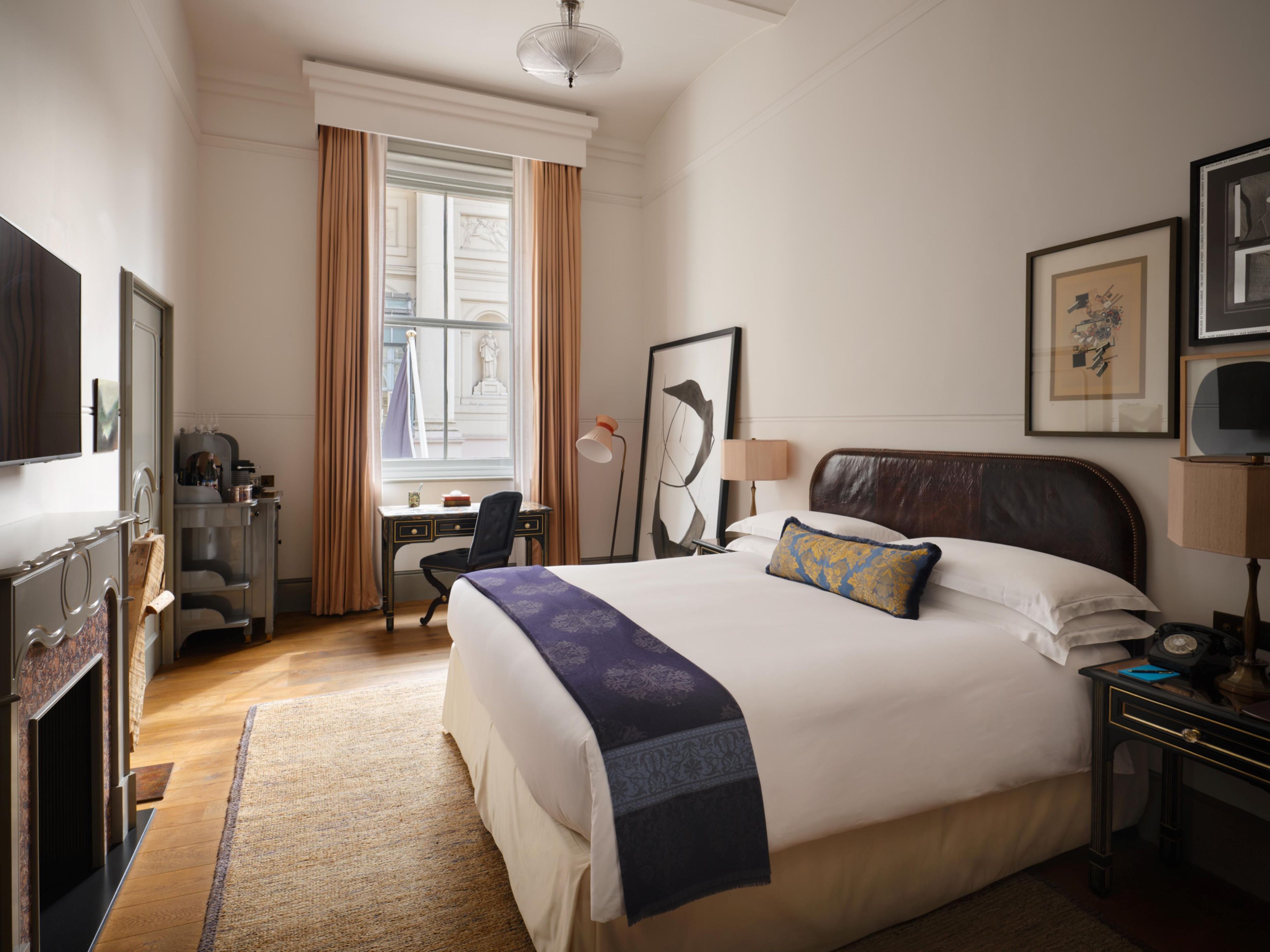 A hotel room with a bed, desk, chair, and a television.