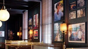 A restaurant interior with booth seating, wall-mounted lamps, and framed pictures.