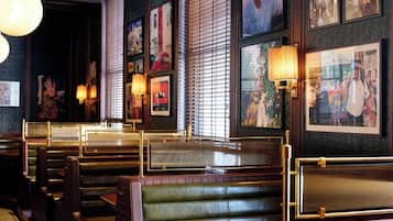 A restaurant interior with booth seating, wall-mounted lamps, and framed pictures.