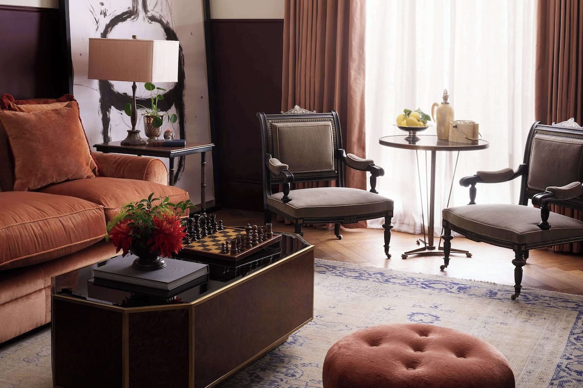 Uma sala de estar moderna com um sofá, poltronas, uma mesa de centro e um quadro na parede.