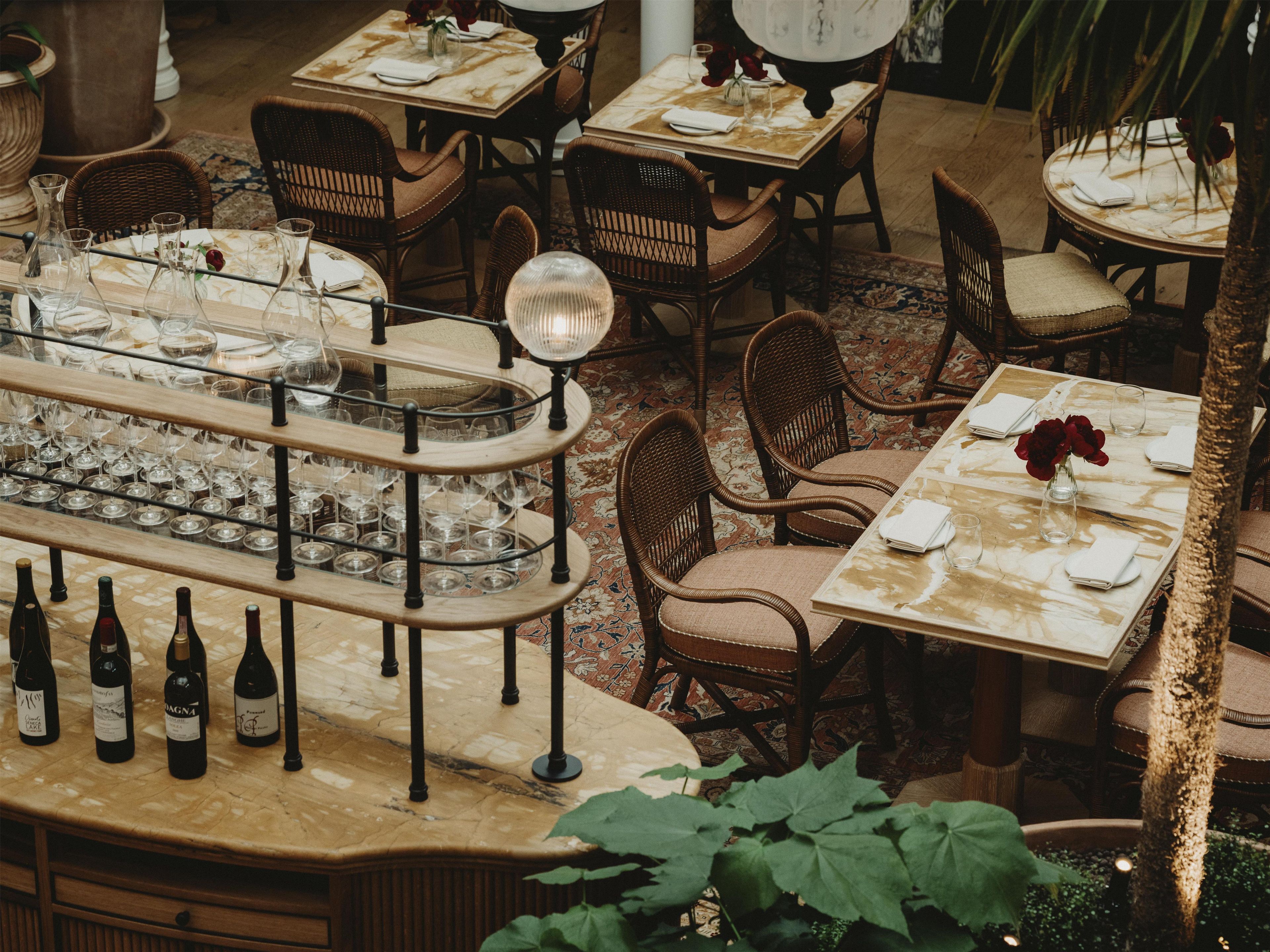 Un ristorante con diversi tavoli e sedie, una dispensa per vini con bottiglie e un pavimento decorato.