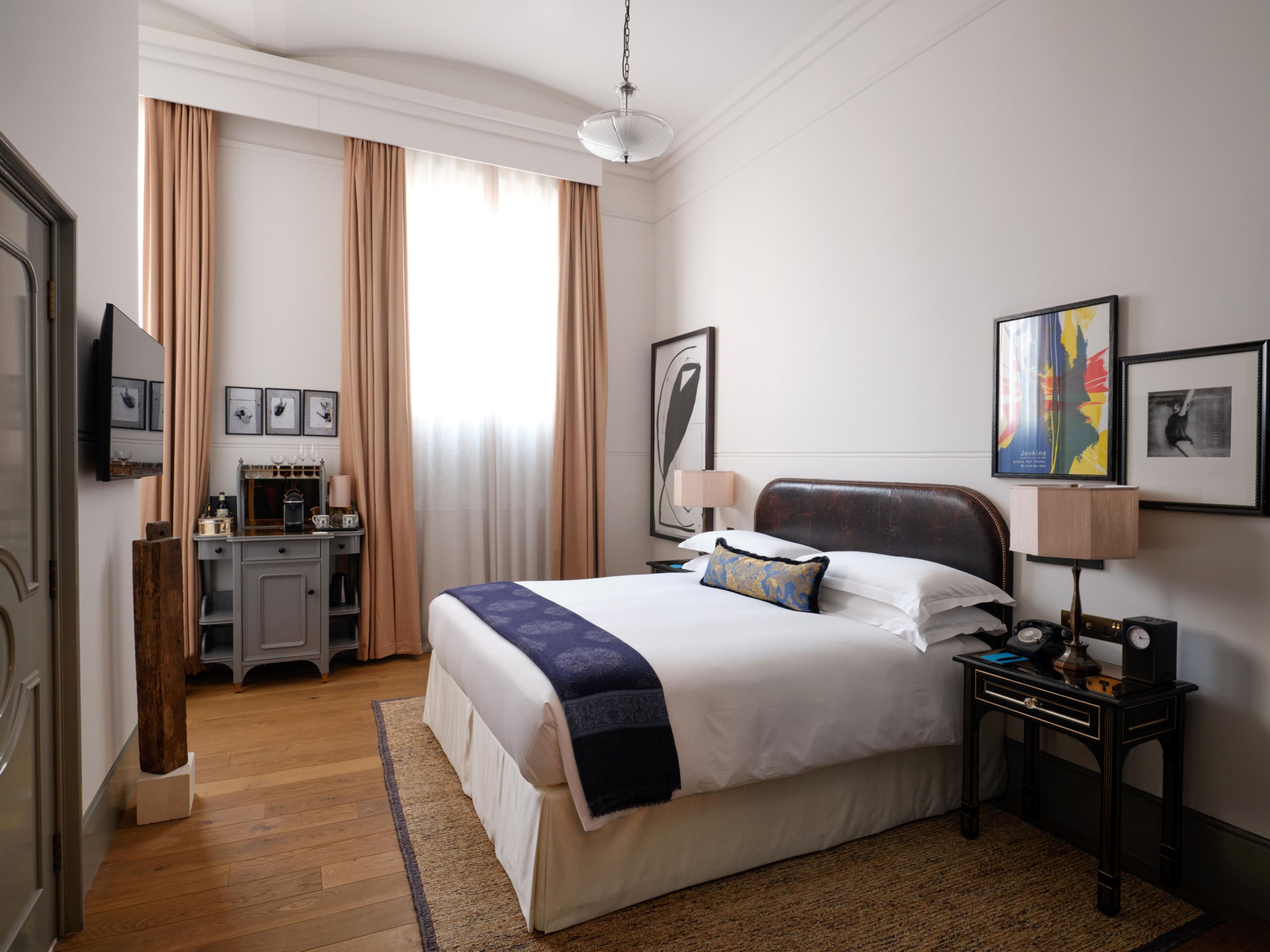 Una camera d'albergo con un letto grande, una scrivania, una televisione e una finestra con tende.