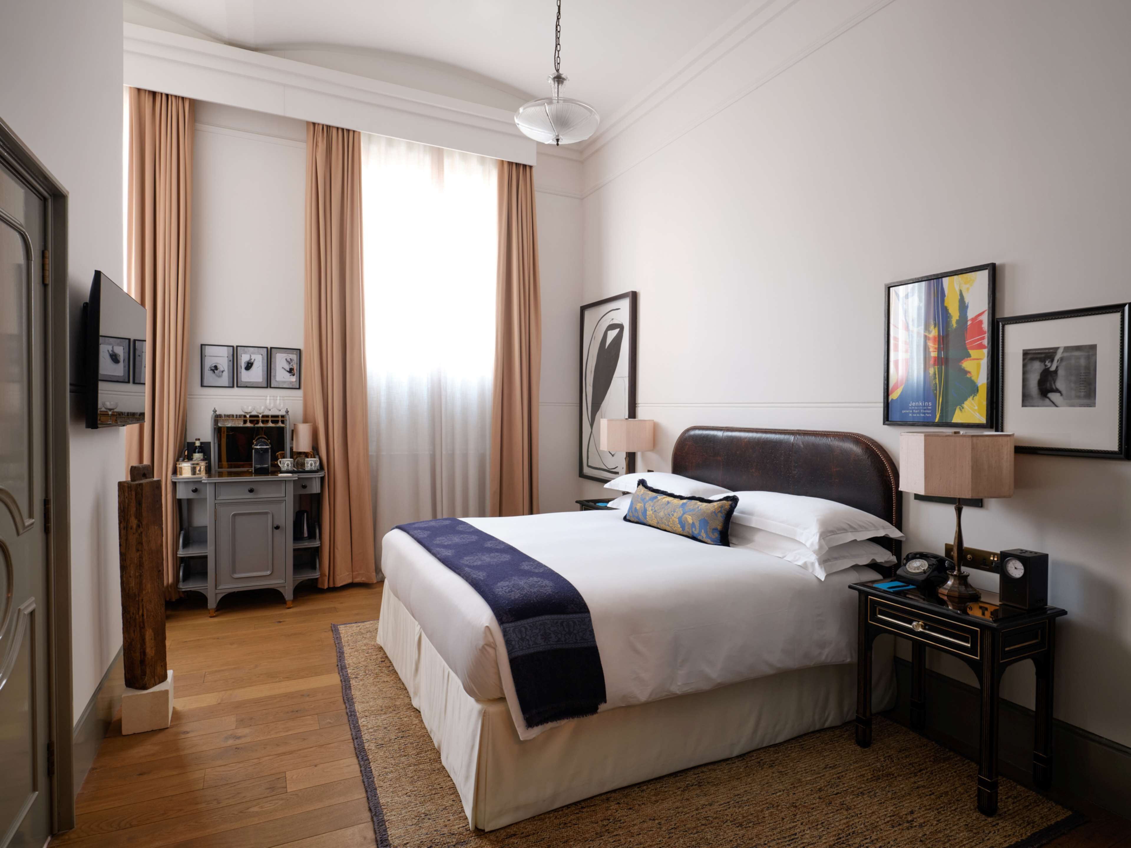 Habitación de hotel con una cama grande, un escritorio con lámpara y un televisor en la pared.