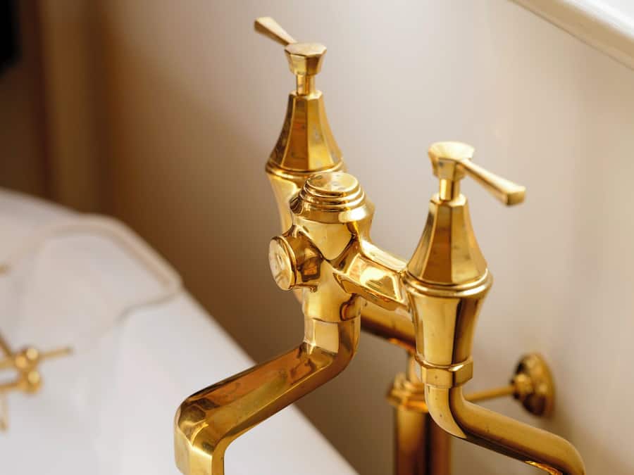 Eine Badewanne mit goldenen Armaturen und weißem Innenraum.