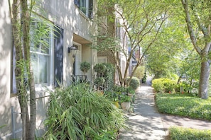 A narrow residential street with houses on both sides, a sidewalk, and trees. - Inviting garden level apartment, The JAD Cox Suite (Savannah)