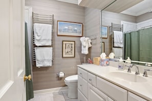 A bathroom with a toilet, sink, and towel racks. - Inviting garden level apartment, The JAD Cox Suite (Savannah)