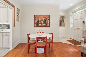 A dining room with a round table, four chairs, and a painting above the table. - Inviting garden level apartment, The JAD Cox Suite (Savannah)
