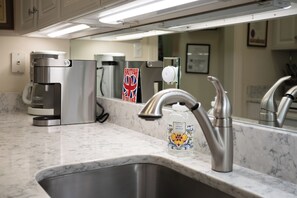 Una cocina moderna con un lavamanos de acero inoxidable, una cafetera y un dispensador de jabón.