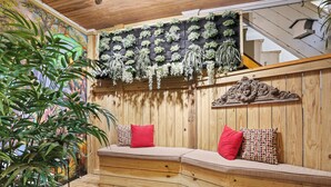 Un banc en bois avec des coussins, un présentoir à plantes fixé au mur et un escalier.