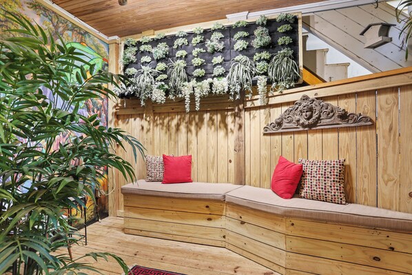 A wooden bench with cushions, a wall-mounted plant display, and a staircase.