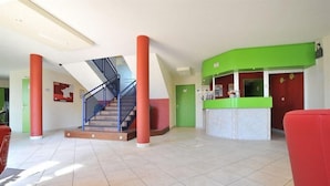 Un vestíbulo con una escalera, una recepción y una silla roja.