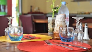 Una mesa de comedor con vajilla transparente, una botella de agua y saleros y pimenteros.