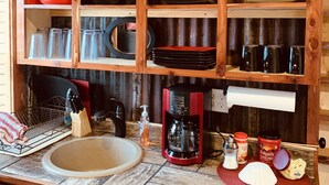 Une cuisine rustique avec des étagères en bois, un évier et divers ustensiles de cuisine.