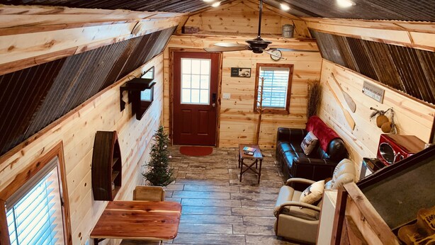 L’intérieur chaleureux d’un chalet avec un plancher en bois, une cheminée, un coin repas et un salon comprenant un canapé et une table basse.