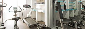 A gym with treadmills, weight machines, and a mirrored wall. - Kamari Beach (Santorini)