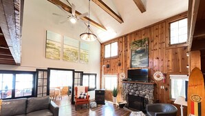 Amplia sala de estar con chimenea de piedra, sofás de cuero y un televisor grande.