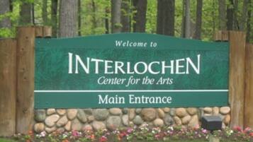 A sign for the Interlochen Center for the Arts with a stone wall and flower bed in front.