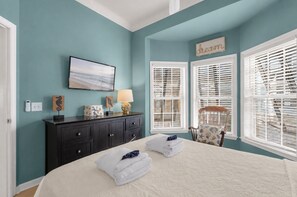 A bedroom with a bed, a dresser, a chair, and a window with blinds.