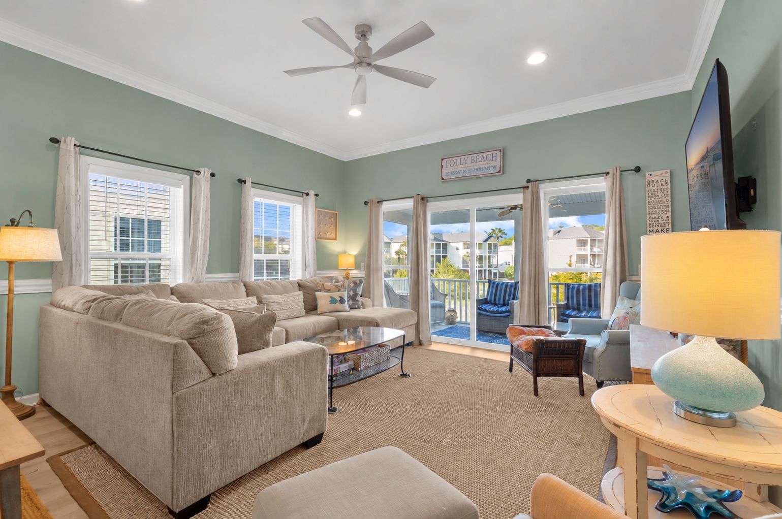 A living room with a sectional sofa, a coffee table, and a view of the outside.