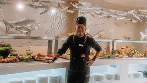 Zona de buffet con arte mural con temática de mariscos y una variedad de platos.