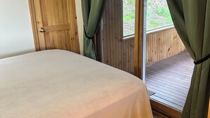 Een slaapkamer met een bed, een houten deur en gordijnen.