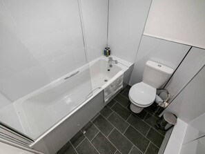 A bathroom with a bathtub, toilet, and dark tiled floor. - ☆Bright Apartment, Near University + City Centre☆ (Dundee)