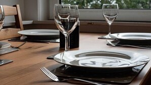 A dining table set with plates, cutlery, and wine glasses, with a window view of trees. - ☆Bright Apartment, Near University + City Centre☆ (Dundee)
