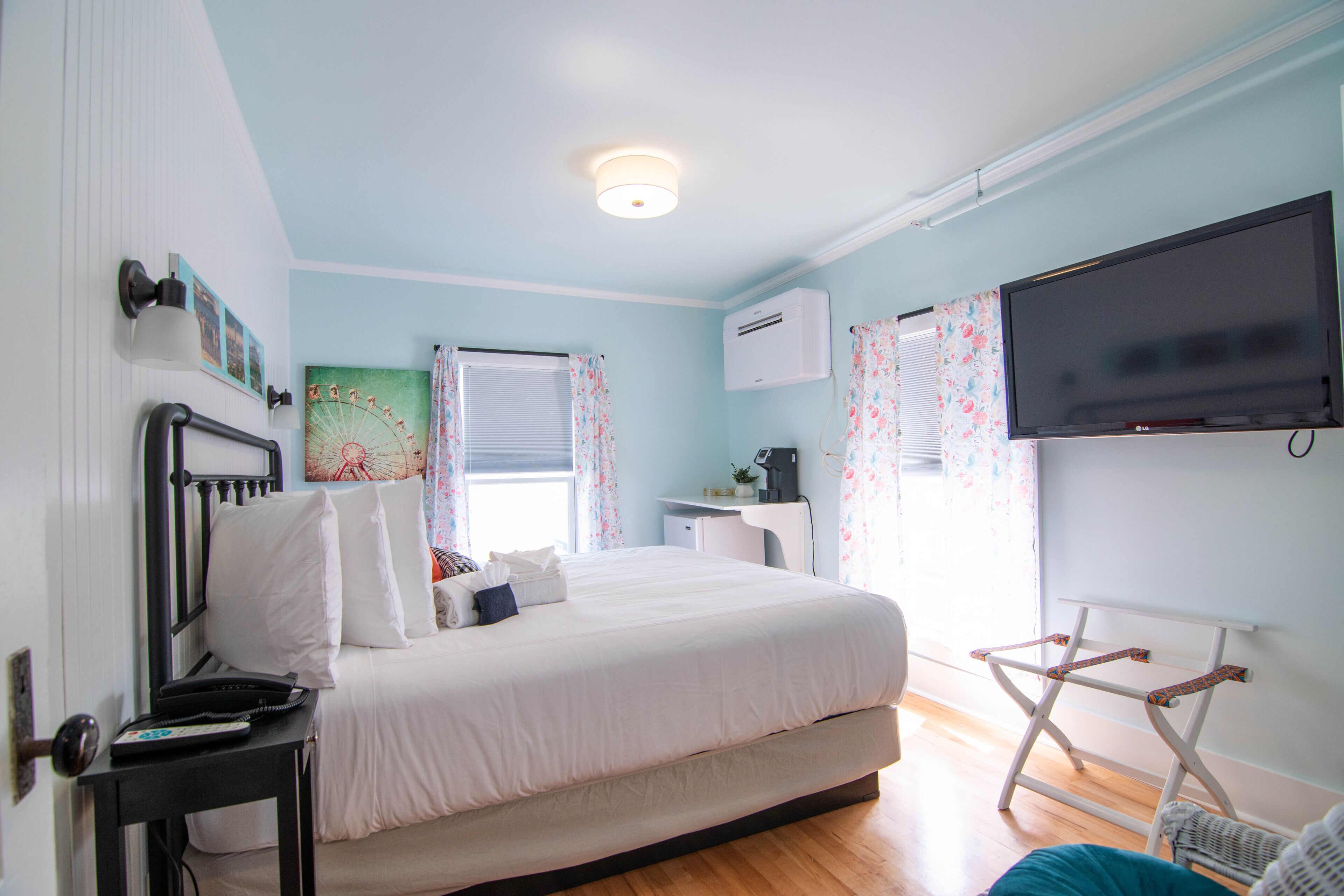 Une chambre à coucher comprenant un lit, un bureau, une chaise, un téléviseur et un appareil de climatisation.