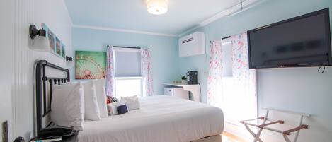Un dormitorio con cama, escritorio, silla, televisor y aire acondicionado.