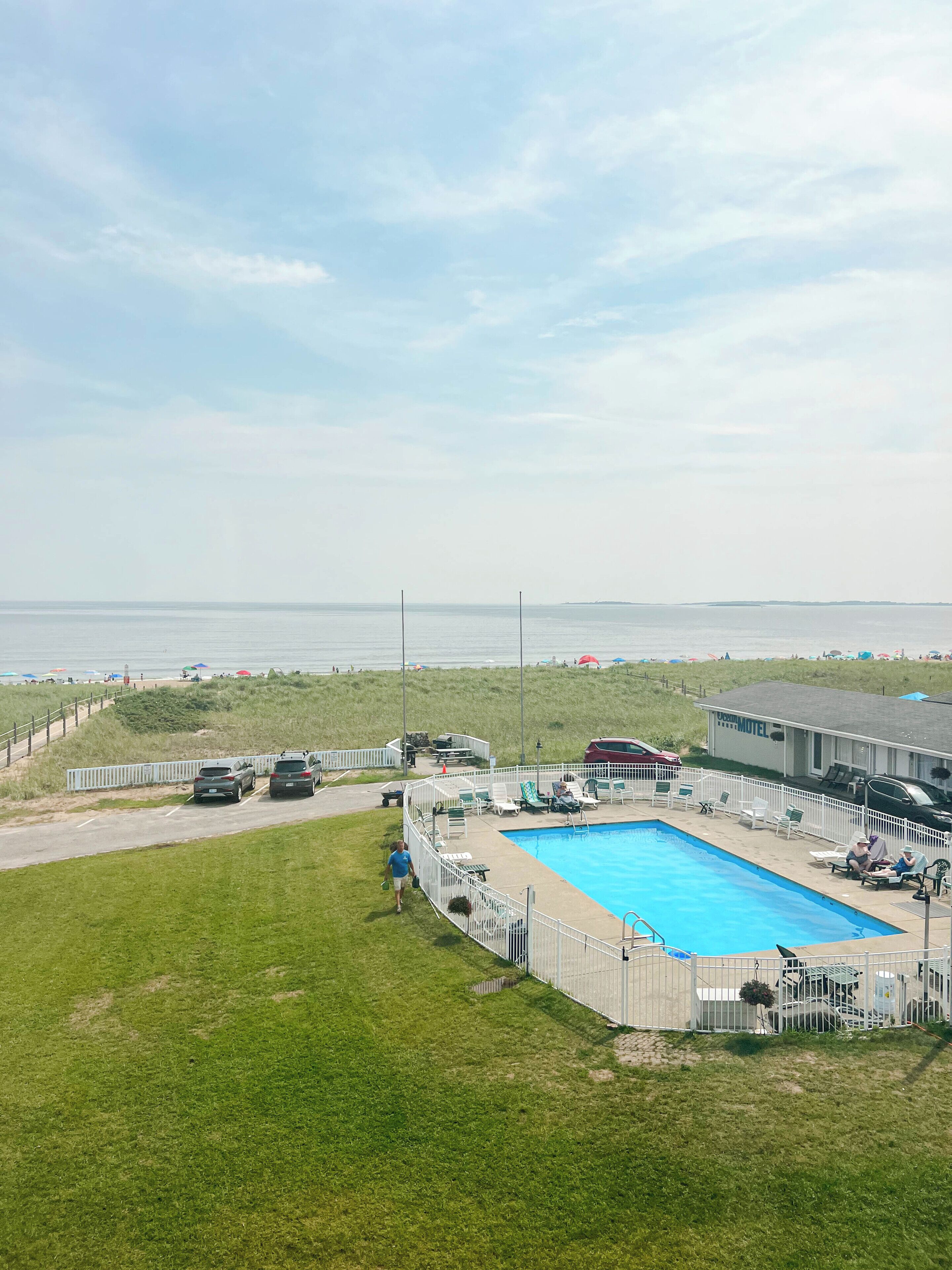 Zona de piscina amb terrassa tancada, gandules i vistes a la platja i l'oceà.