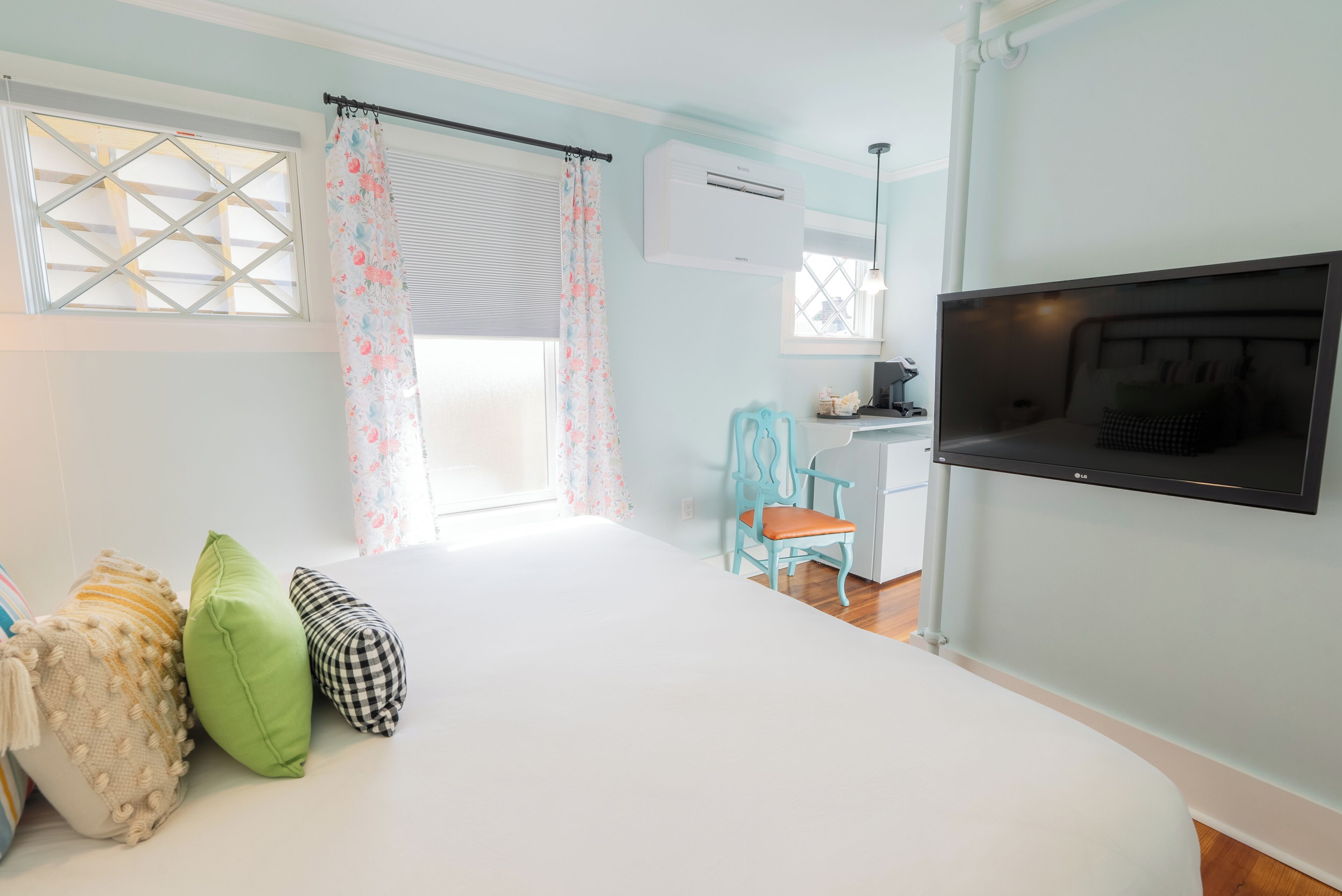 A bedroom with a bed, a TV, a desk, and a chair.