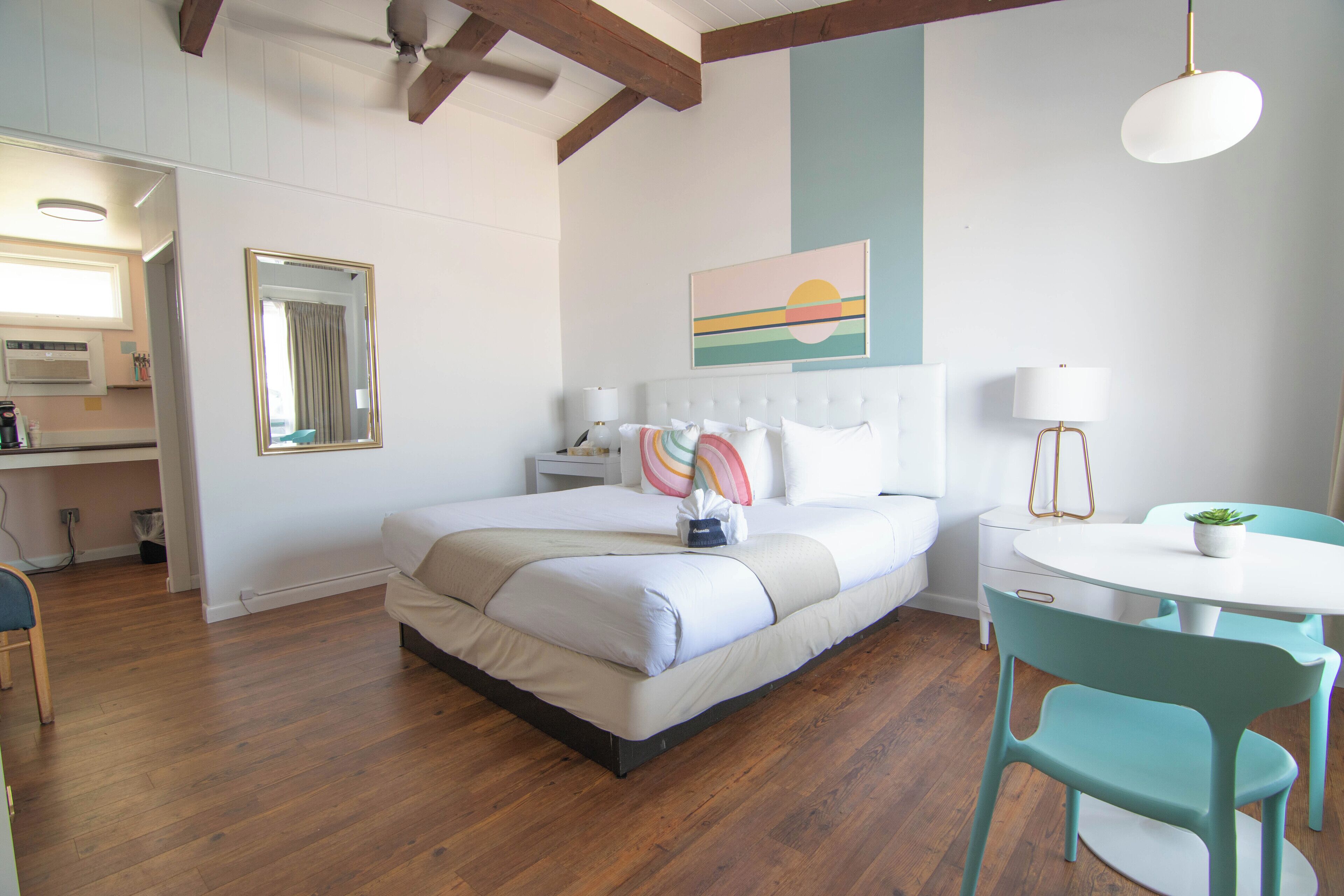 A bedroom with a bed, bedside table, lamp, and a small table with a plant.