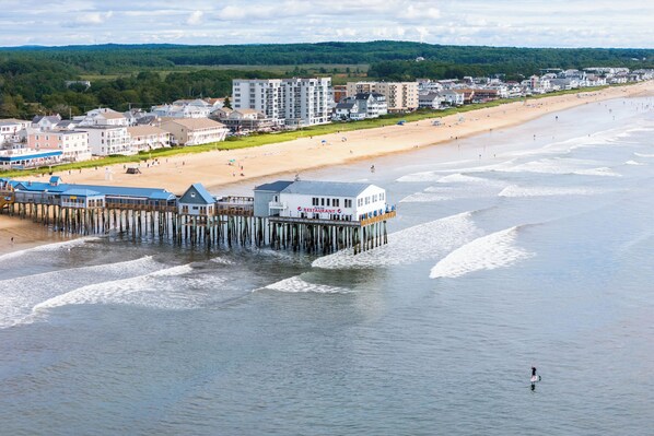 Eine Pier direkt am Strand mit einem Restaurant, neben einem Sandstrand und Wohngebäuden.