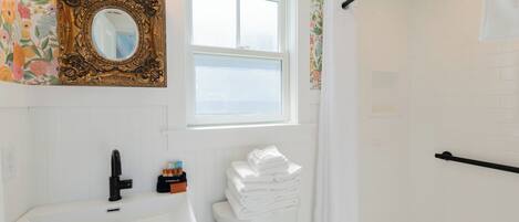 A bathroom with a white sink, a toilet, a mirror with an ornate frame, and a window.