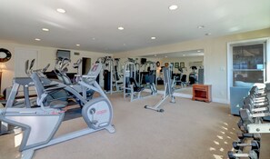 Ein Heimfitnessraum mit verschiedenen Trainingsgeräten, darunter Laufbänder, Crosstrainer und Kurzhanteln.