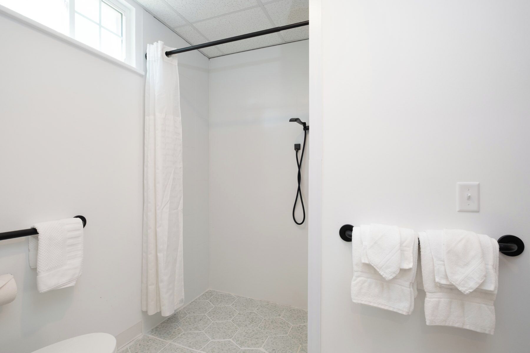 Et badeværelse med brusebad, toilet og håndklædetørrestativ.