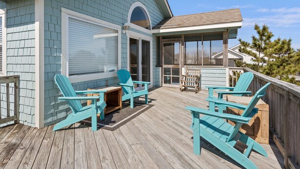 Een overdekt terras met houten stoelen en een tafel, een overdekte patio en uitzicht op de omgeving.