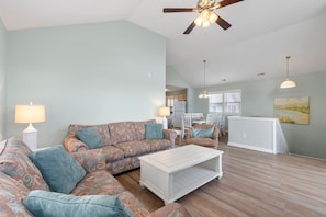 A spacious living room with a sofa set, a coffee table, and a ceiling fan.