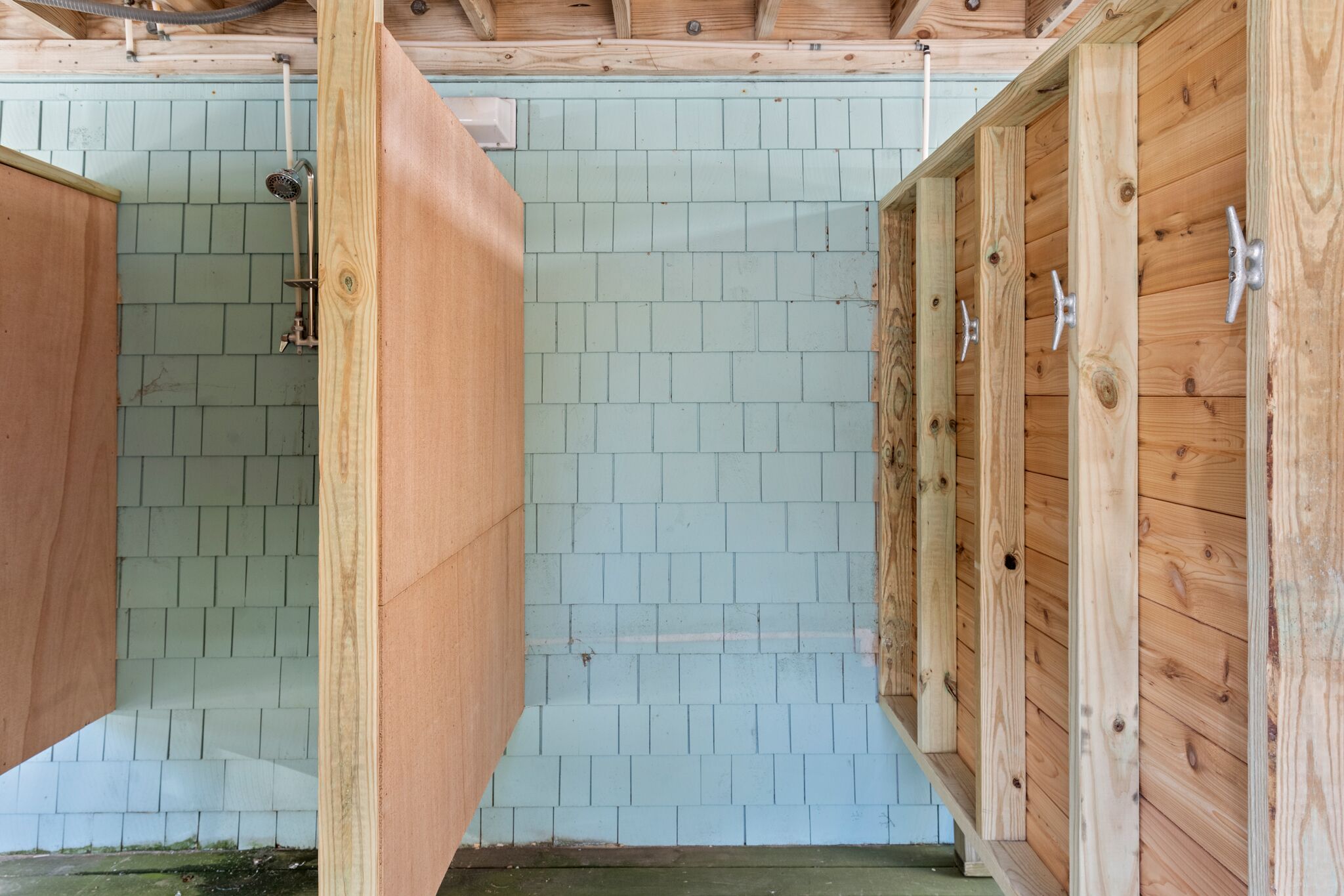 A wooden stall with a tiled floor, a metal door, and a wooden beam structure.