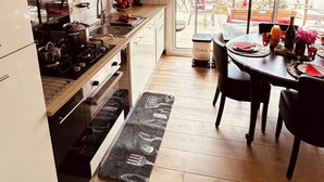 A modern kitchen with a view of the sea, wooden flooring, and a dining area with a table set for two.