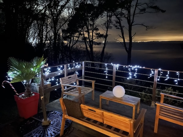 An outdoor deck with wooden furniture, string lights, and a potted plant. - House With Direct Sea Access On 18000 M2 Of Woodland (Argol)