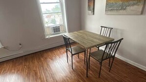 A dining area with a table and chairs, a window with a view, and two paintings on the wall. - TwinCity 1 BR/1 BA- Minutes to NYC!  (Jersey City)