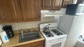 A kitchen with wooden cabinets, a gas stove, a sink, and a refrigerator. - TwinCity 1 BR/1 BA- Minutes to NYC!  (Jersey City)